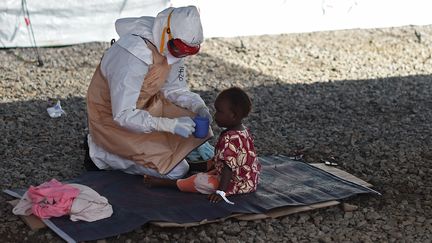 Un membre des équipes médicales soigne un enfant atteint de l'épidémie Ebola, au centre de traitement de Kenama, au Sierra Leone, le 15 noivembre 2014. (FRANCISCO LEONG / AFP)