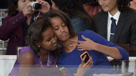 Sasha (G) et Malia Obama, les filles du pr&eacute;sident am&eacute;ricain Barack Obama, se prennent en photo pendant la c&eacute;r&eacute;monie d'investiture de leur&nbsp;p&egrave;re &agrave; Washington (Etats-Unis), le 21 janvier 2013. (JOE KLAMAR / AFP)