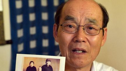 Yohachi Nakajima, 73 ans, tient une photo de ses parents adoptifs chinois (AFP/YOSHIKAZU TSUNO)