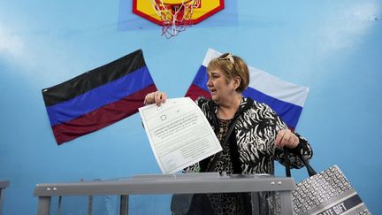 Une habitante de Louhansk (Ukraine) dépose un bulletin dans une urne à l'occasion d'un référendum d'annexion, le 27 septembre 2022. (STRINGER / ANADOLU AGENCY / AFP)