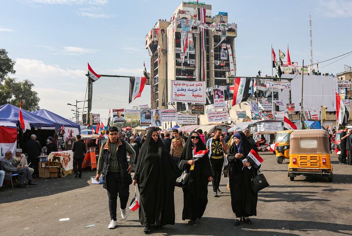 Des femmes tiennent des drapeaux irakiens, sur la place Tahrir, devant le bâtiment occupé par les manifestants, "le restaurant turc", le 23 novembre 2019, à Bagdad (Irak).&nbsp; (SABAH ARAR / AFP)