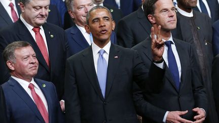 Le président américain Barack Obama indique que lui et ses homologues attendent encore deux retardataires, avant de poser pour la photo de famille du sommet nucléaire le 1er avril 2016 à Washington. Au premier plan, il est entouré du roi Abdallah de Jordanie (à gauche), de l'Ukrainien Petro Poroshenko (à gauche, au-dessus de lui), du Finnois Sauli Niinisto (au centre, au-dessus de lui) et du Premier ministre danois Mark Rutte (à droite).     
 (REUTERS/Jonathan Ernst )