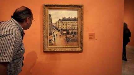 Un visiteur du musée Thyssen-Bornemisza (Madrid) regarde le tableau "Rue Saint-Honoré dans l'après-midi, effet de pluie", dont une famille juive spoliée réclame la restitution. (MARIANA ELIANO / AP /SIPA)