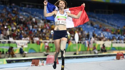 Drapeau tricolore sur les épaules, la Française Marie Amélie Le Fur entame un nouveau tour de piste, le 12 septembre, après avoir remporté le 400 m au stade olympique de Rio pendant les jeux paralympiques. (CHRISTOPHE SIMON / AFP)