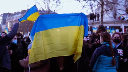 Des manifestants brandissent des drapeaux de l'Ukraine lors d'un rassemblement de soutien à Paris, le 24 février 2022. (ANNA MARGUERITAT / HANS LUCAS / AFP)