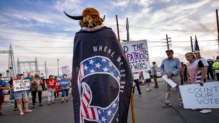 Le militant QAnon Jake A., surnommé "le loup de Yellowstone", manifeste aux côtés de militants pro-Trump devant le centre où a lieu le dépouillement de la présidentielle américaine, le 5 novembre 2020 à Phoenix, dans l'Arizona. (OLIVIER  TOURON / AFP)