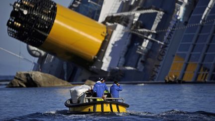 Une équipe technique passe à proximité du "Costa Concordia", le 26 janvier 2012 près de l'île de Giglio (Italie). Le paquebot a commencé à sombrer treize jours plus tôt, après&nbsp;s'être trop approché des côtes. Trente-deux personnes sont mortes dans cet accident. (FILIPPO MONTEFORTE / AFP)