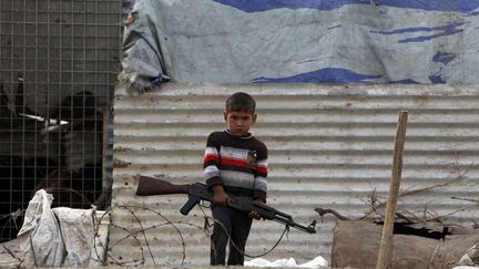 Un jeune gar&ccedil;on porte un fusil AK-47 &agrave; Nassiriya (Irak), le 15 f&eacute;vrier 2013. (THAIER AL-SUDANI / REUTERS)