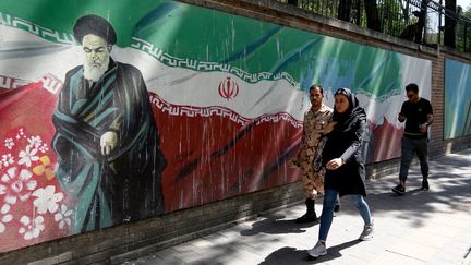 Des Iraniens passent devant une fresque représentant l'ayatollah Ruhollah Khomeini, à Téhéran, le 22 juin 2019. (ATTA KENARE / AFP)