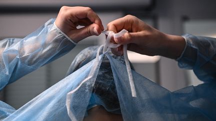 Une infirmière enfile une blouse&nbsp;avant d'entrer dans la chambre d'un patient infecté par le Covid-19 dans le service de réanimation de l'hôpital européen AP-HP Georges Pompidou, à Paris, le 6 avril 2021. (ANNE-CHRISTINE POUJOULAT / AFP)