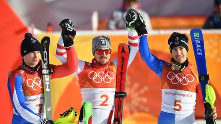 Les skieurs français Alexis Pinturault (à gauche) et Victor Muffat-Jeandet (à droite) entourent l'Autrichien Marcel Hirscher, après leurs médailles d'argent et de bronze dans l'épreuve du combiné des Jeux olympiques de Pyeongchang, le 13 février 2018. (FABRICE COFFRINI / AFP)