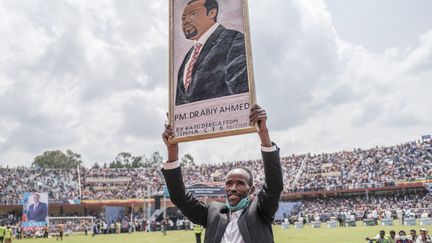 Un homme tient un portrait du Premier ministre éthiopien, Abiy Ahmed, dans un stade de Jimma le 16 juin 2021, lors de la campagne électorale, avant le vote du 21 juin 2021. (EDUARDO SOTERAS / AFP)