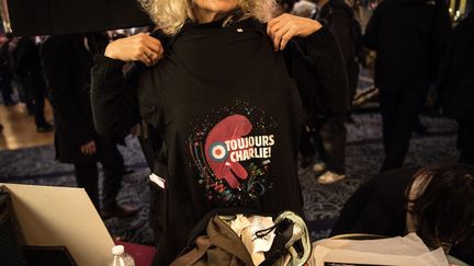 Une femme montre un teeshirt "Toujours Charlie" pendant le rassemblement aux Folies Bergères, le samedi 6 janvier à Paris. (CHRISTOPHE ARCHAMBAULT / AFP)