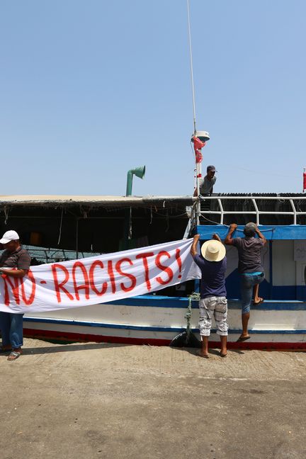 Des pêcheurs tunisiens accrochent une banderole "Pas de racistes" à un bateau dans le port de Zarzis, en Tunisie, le 6 août 2017 (FATHI NASRI / AFP)