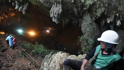 Un homme observe les opérations de secours pour retrouver 13 personnes disparues dans la grotte de Tham Luang en Thaïlande, le 27 juin 2018. (LILLIAN SUWANRUMPHA / AFP)