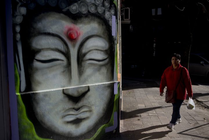 Une femme passe devant un graff représentant Buddha à Buenos Aires, juin 2015
 (EITAN ABRAMOVICH / AFP)