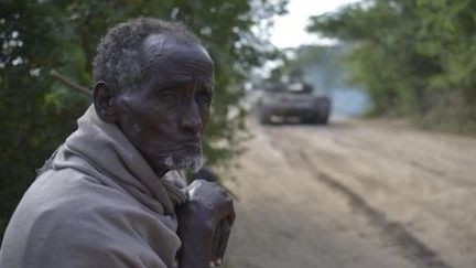 Un Somalien regarde passer les chars des troupes ougandaises de la Mission de l'Union africaine en Somalie (Amisom) et celles de l'armée nationale somalienne, à Janaale, en Somalie, le 14 février 2013. Le groupe islamiste shebab a été chassé des villes de Janaale, Aw Dheegle et Barrire par les forces alliées dans le cadre de l'opération «Boot on the Ground». (AU UN IST PHOTO / AFP PHOTO / TOBIN JONES )