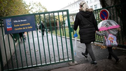 Une femme et un enfant arrivent le 30 septembre 2019 à l'école maternelle Cavelier de la Salle, une des deux écoles de Rouen où des traces de suie ont été retrouvées sur des rebords de fenêtres. (LOU BENOIST / AFP)