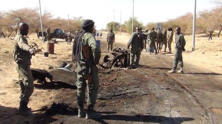 Des soldats maliens observent la sc&egrave;ne apr&egrave;s une attaque suicide men&eacute;e par un jihadiste pr&egrave;s de l'a&eacute;roport de Tombouctou au mali, le 21 avril 2013. (SIPA)