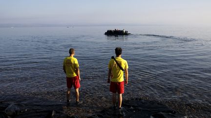 Des secouristes b&eacute;n&eacute;voles espagnols regardent un bateau de migrants accoster sur les c&ocirc;tes grecques de l'&icirc;le de Lesbos, le 27 septembre 2015. (YANNIS BEHRAKIS / REUTERS)