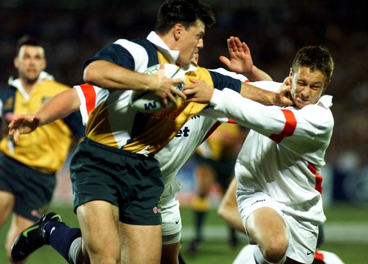 Le rugbyman anglais Jonny Wilkinson (en blanc, à droite) se fait balayer par le centre australien Matt Burke (à gauche, en jaune) lors d'un test-match entre l'Australie et l'Angleterre, le 6 juin 1998 à Brisbane (Australie). (MARK BAKER / X00017)