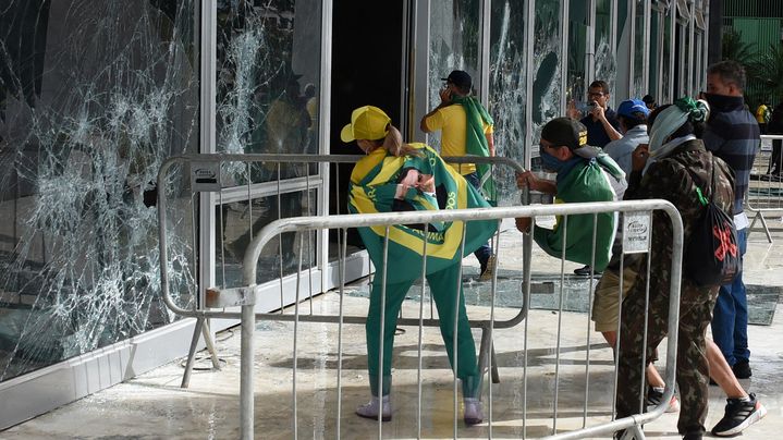 Des partisans de Bolsonaro forcent les vitres de la Cour surpême de Brasilia, le 8 janvier 2023 en utilisant des barrières de sécurité comme bélier. (TON MOLINA / AFP)