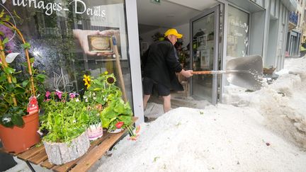 Un habitant de Plombière-les-Bains (Vosges) dégage la grêle qui s'est accumulée dans son commerce, le 29 juin 2021. (MAXPPP)