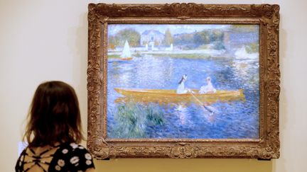 Une femme regarde un tableau de Renoir. (FRANCOIS GUILLOT / AFP)