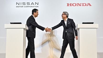 Les présidents de Nissan et Honda, Makoto Uchida et Toshihiro Mibe, se saluent avant une conférence de presse commune à Tokyo, le 1er août 2024. (RICHARD A. BROOKS / AFP)