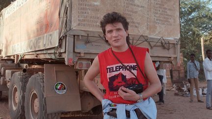 Daniel Balavoine pose devant le camion avec lequel il participait à un "rallye du cœur" distribuant des pompes à eau sur le parcours du Paris-Dakar, le 8 janvier 1986
 (Daniel Janin, Dominique Faget / Archives / AFP)