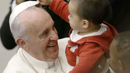 Un jeune gar&ccedil;on enl&egrave;ve au&nbsp;pape Fran&ccedil;ois sa calotte lors d'une rencontre avec des enfants au Vatican, le 14 d&eacute;cembre 2013. (GREGORIO BORGIA / AP / SIPA)