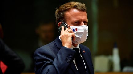 Le président de la République, Emmanuel Macron, téléphone durant un sommet de l'Union européenne à Bruxelles (Belgique), le 20 juillet 2020. (JOHN THYS / POOL / AFP)