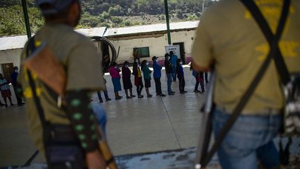 Des électeurs font la queue pour voter tandis que la police monte la garde dans un bureau de vote à Ayahualempa dans l'État de Guerrero (6 juin 2021). (PEDRO PARDO / AFP)