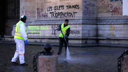 Des agents de la ville de Paris nettoient l'Arc de triomphe et ses abords, le 2 décembre 2018, au lendemain du rassemblement des "gilets jaunes" sur la place de l'Etoile. (GEOFFROY VAN DER HASSELT / AFP)