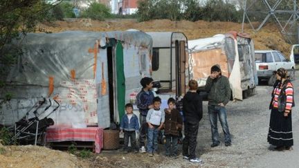 Une famille de roms devant le champ où ils logeaient avant une expulsion, le 25 mars 2011. (FRANK PERRY / AFP)