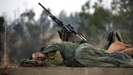 Un soldat isra&eacute;lien se repose sur le toit d'un tank stationn&eacute; pr&egrave;s de la fronti&egrave;re avec la bande de Gaza, le 19 novembre 2012. (MENAHEM KAHANA / AFP)