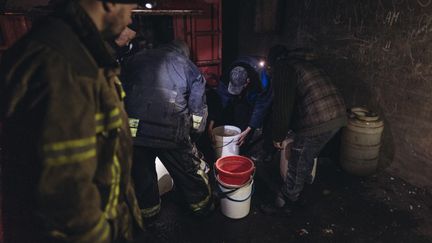 Des habitants de Bakhmout (Ukraine) éteignent un incendie causé par un bombardement le 22 décembre 2022. (DIEGO HERRERA CARCEDO / ANADOLU AGENCY via AFP)