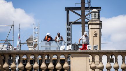 Des ouvriers sur le toit de l'Elysée, à Paris, le 29 juillet 2022. (XOSE BOUZAS / HANS LUCAS / AFP)