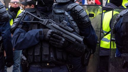 Un policier tient un lanceur de balles de défense, le 29 décembre 2018, lors d'une manifestation des "gilets jaunes", sur les Champs-Elysées à Paris. (KARINE PIERRE / HANS LUCAS / AFP)