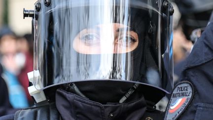 Une policière casquée se tient près des Champs-Elysées. (ZAKARIA ABDELKAFI / AFP)