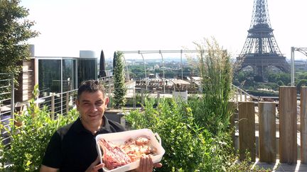 Hugo Desnoyer avec un choix de morceaux de viande pour son barbecue devant la Tour Eiffel. (Laurent Mariotte / Radio France)