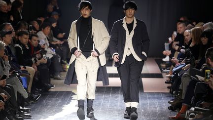 Maquillés avec des cicatrices, les yeux cernés, les cheveux teints par endroits, les mannequins du défilé Yohji Yamamoto avaient des allures zombies mais en version dandy. Le look entièrement noir si cher au créateur japonais est bien entendu de rigueur. Ce noir, tout à la fois élégant et moderne, qu'il affectionne depuis toujours, peut être aussi branché. Ici coutures à l'envers et superpositions de couches de vêtements sont de mises pour une silhouette toujours élégante avec nonchalence. Le créateur joue aussi avec les couleurs : une touche de rouge sur le devant d'une veste, des vestes mêlant différentes tonalités bleues, faites de matières contrastées en patchworks et de toiles déchirées. Une collection qui joue sur l'idée du souvenir et de l'inachevé dans un esprit bohème !
 (FRANCOIS GUILLOT / AFP)