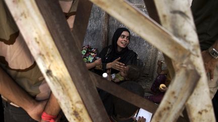 Une femme irakienne, qui a fui les combats entre l'armée irakienne et les djihadistes à Mossoul, en Irak, reste assise dans les décombres, un enfant dans ses bras, en attendant d'être redirigée vers une zone sécurisée, le 8 juillet 2017. (FADEL SENNA / AFP)