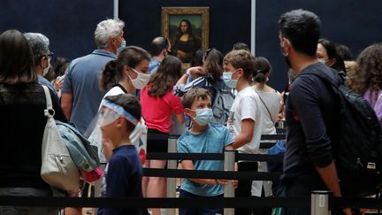 Des&nbsp;visiteurs&nbsp;portant un masque font la queue pour voir&nbsp;"La Joconde", lors de la réouverture du Louvre, à Paris, le 6 juillet 2020, après&nbsp;quelque&nbsp;quatre mois de fermeture liée au coronavirus. (CHARLES PLATIAU / REUTERS)