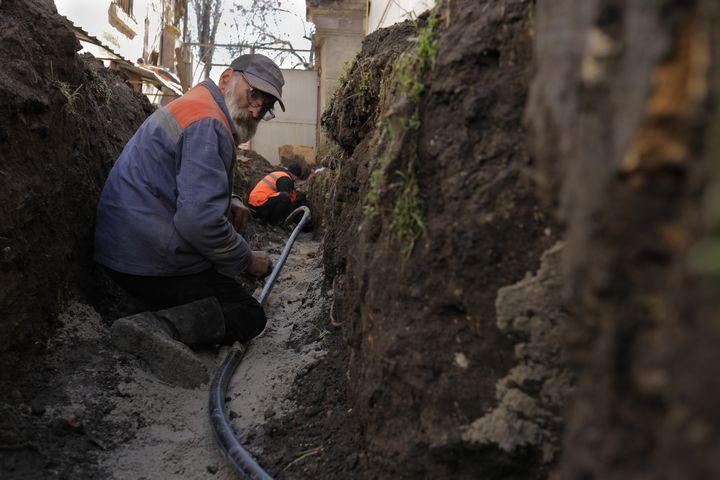 Des ouvriers remplacent une canalisation d'acier oxydée par une autre en plastique, le 27 mars 2023, dans un jardin de Mykolaïv (Ukraine). (MATHIEU DREUJOU / FRANCE TELEVISIONS)