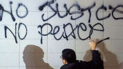 Un manifestant écrit un graffiti (Pas de Justice, pas de paix), lundi 24 novembre à Oakland (Californie) après le verdict de Ferguson.
 (Noah Berger/AP/SIPA)