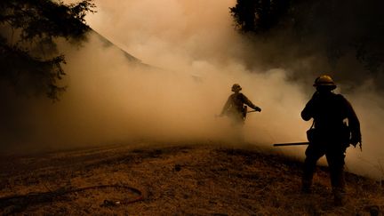 Deux pompiers avancent à travers des nuages de fumée alors que les flammes se rapprochent d'une maison à Lakeport en californie, le 30 juillet 2018.&nbsp; (JOSH EDELSON / AFP)