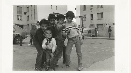 Garçons jouant aux pistolets, sur le terrain proche de la rue des Arbousiers, Carros, avril 1983, Tirage gélatino-argentique. (LES ARTS DECORATIFS / BERNARD GILLE)