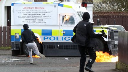 Des jeunes masqués attaquent un Land Rover de la police avec des bombes incendiaires, après que des républicains ont participé à une marche pour commémorer l'insurrection de Pâques de 1916, à Londonderry (Irlande du Nord), le 10 avril 2023. (PAUL FAITH / AFP)