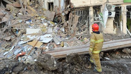 Un secouriste devant un immeuble endommagé par une frappe à Kharkiv (Ukraine), le 16 mars 2022.&nbsp; (SERGEY BOBOK / AFP)